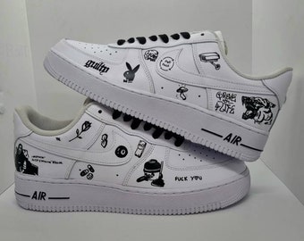 May include: White leather sneakers with black custom drawings and text, including "Guilty", "Fuck You", "Grove St. Life", and "Air" on the sides.