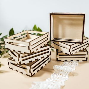 Op de afbeelding: Een stapel van vier kleine houten kisten met een bruine vlek. De kisten zijn gemaakt van dun triplex en hebben een eenvoudig ontwerp met een paar horizontale latten.