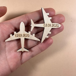 May include: Two wooden airplane shapes with the date "02.08.2025" engraved on each.