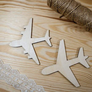 Pode incluir: Duas formas de avião de madeira sobre uma superfície de madeira marrom claro. Os aviões são recortados e têm um acabamento de madeira natural.