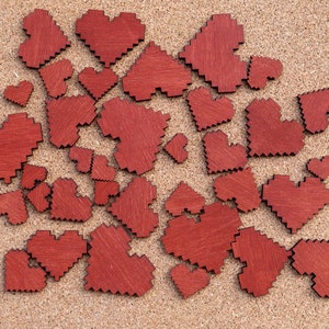 May include: A corkboard with a collection of red wooden hearts of various sizes arranged in a random pattern.
