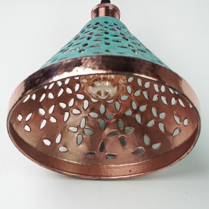 Worm's eye view of cone copper lights combining hand-carved cut-out pattern with green patina finish and small strip of hand-hammered pattern with polished copper finish, with natural copper finish interior.