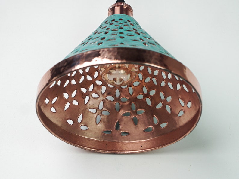 Worm's eye view of cone copper lights combining hand-carved cut-out pattern with green patina finish and small strip of hand-hammered pattern with polished copper finish, with natural copper finish interior.