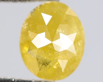 Puede incluir: Un diamante redondo amarillo con un corte facetado. El diamante está sujeto con unas pinzas.