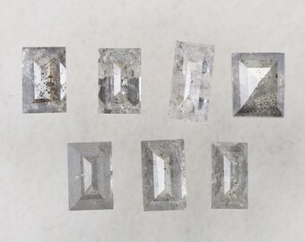 May include: Seven clear, rectangular, faceted gemstones on a white background. The gemstones are all different sizes and shapes.