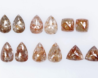 May include: A collection of ten rough cut diamonds in various shapes, including pear, cushion, and triangular. The diamonds are a light brown color with a translucent appearance.