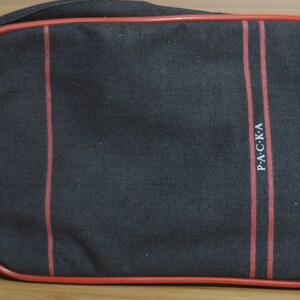 May include: Black wash bag with red trim and the word "P.A.C.K.A" printed in white.