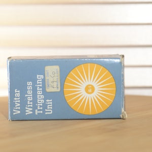 May include: A blue box with the text "Vivitar Wireless Triggering Unit" and a yellow sunburst design. The box has a price tag that says "Camera Craft £9.50".