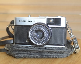Cámara compacta vintage Olympus Trip 35 con estuche, tapa de objetivo y manual.