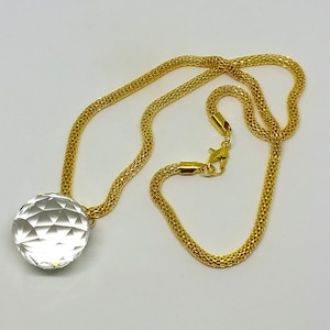 May include: A gold chain necklace with a clear, faceted crystal pendant. The chain is a delicate, woven design.