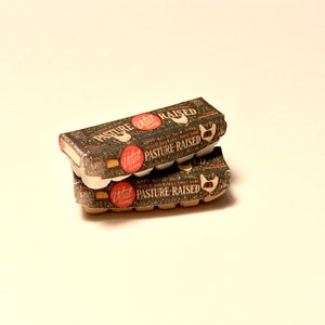 May include: Two cartons of Vital Farms pasture-raised eggs. The cartons are stacked on top of each other. The top carton is brown with white text and a red circle with the Vital Farms logo. The bottom carton is brown with white text and a red circle with the Vital Farms logo.