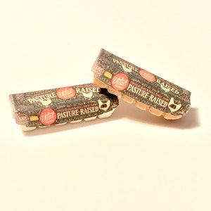 May include: Two cardboard egg cartons with a brown and white patterned design. The cartons are labeled "Vital Farms Pasture Raised" in red and white text.