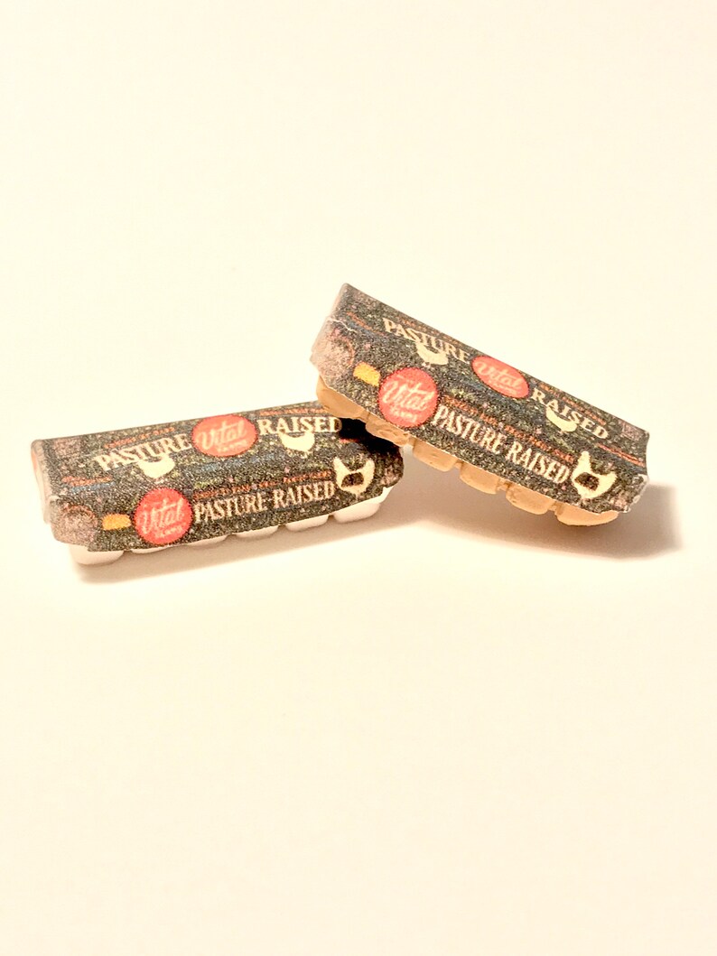 May include: Two cardboard egg cartons with a brown and white patterned design. The cartons are labeled "Vital Farms Pasture Raised" in red and white text.