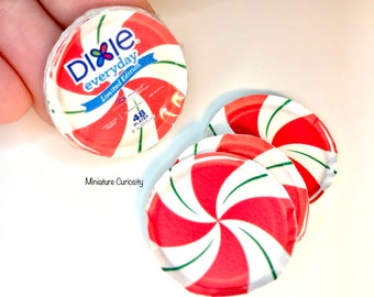 May include: Miniature Dixie everyday plates with a red and white peppermint swirl design. The plates are packaged and feature the Dixie logo and text. The plates are a limited edition.