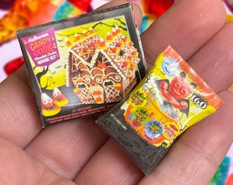May include: Two miniature Halloween candy boxes. One box is for a candy corn gingerbread house kit. The other box is for Sour Patch Kids candy. Both boxes are black with colorful graphics.
