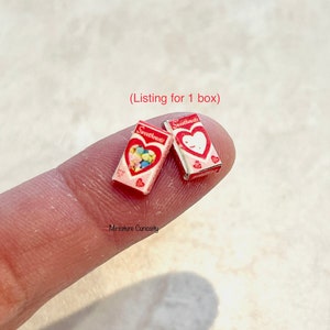 May include: Two miniature boxes of candy hearts, each with a red heart and the word "Sweethearts" printed on the front. The boxes are pink and white with a red border. The text "(Listing for 1 box)" is printed above the boxes.