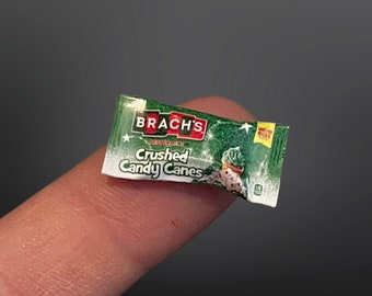 May include: A small green and white package of Brach's Crushed Candy Canes. The package has a red star and a green candy cane on it.