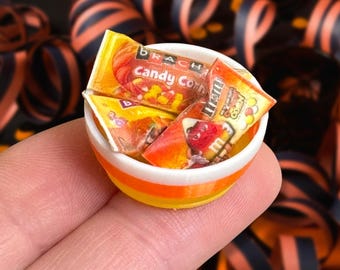 May include: A miniature orange and white candy corn bowl filled with miniature bags of Brach's Candy Corn and M&M's Minis Candy Corn.