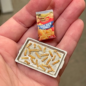 Op de afbeelding: Een miniatuur bakplaat gevuld met goudbruine, knapperige Ore-Ida Golden Crinkles aardappelchips. De zak chips is ook te zien op de afbeelding, met de tekst "Ore-Ida Golden Crinkles 32 oz."
