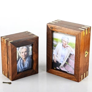 Może przedstawiać: Dwa drewniane ramki na zdjęcia z mosiężnymi akcentami. Ramki są zamknięte i każda zawiera zdjęcie kobiety. Większa ramka ma napis "Dony Avenue" z przodu.