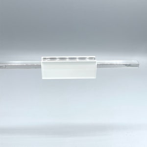 May include: A modern, minimalist light fixture featuring a rectangular frosted glass shade and a sleek, metallic bar. The fixture is designed for a clean, contemporary aesthetic, suitable for various interior design styles.