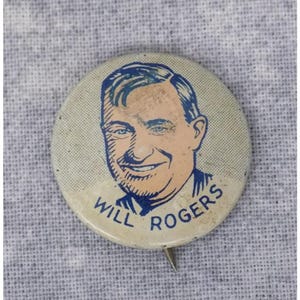 May include: A vintage button featuring a cartoon portrait of Will Rogers. The button is white with blue lettering and a blue outline around the portrait. The text on the button reads "Will Rogers".