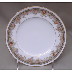 Puede incluir: Un plato de porcelana blanca con un borde dorado y un patrón floral en tonos de rosa, amarillo y verde.