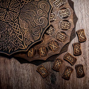 May include: A dark brown wooden circular board featuring intricate laser-engraved Celtic knotwork and swirling patterns, accompanied by a matching wooden base with circular cutouts and several small rectangular wooden tiles engraved with runic symbols.
