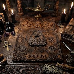 Op de afbeelding: Een houten spirit board met een alfabet, cijfers en de tekst GOOD BYE, inclusief een bijpassende planchette. De scène bevat zwarte kaarsen, glazen flesjes, een ankh-hanger, een koperen olielamp, een verweerd boek en een metalen dolk.