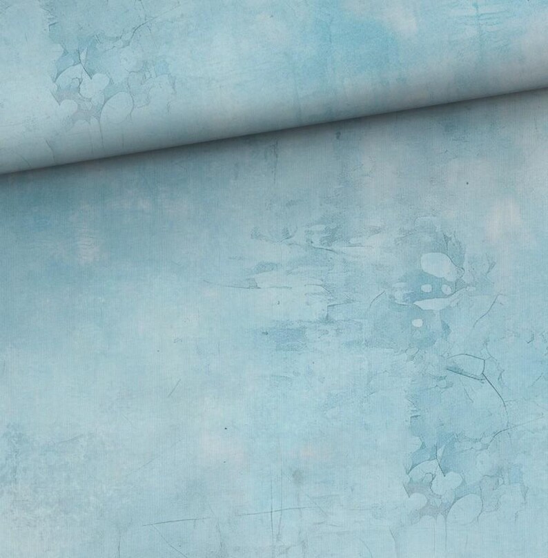 May include: A roll of light blue fabric with a textured, distressed appearance. The fabric has a watercolor-like effect with variations in tone and visible imperfections, creating a vintage or artistic aesthetic.