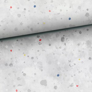 May include: A white fabric with a gray watercolor splatter pattern. The fabric is decorated with small red, blue, and yellow dots and white stars.