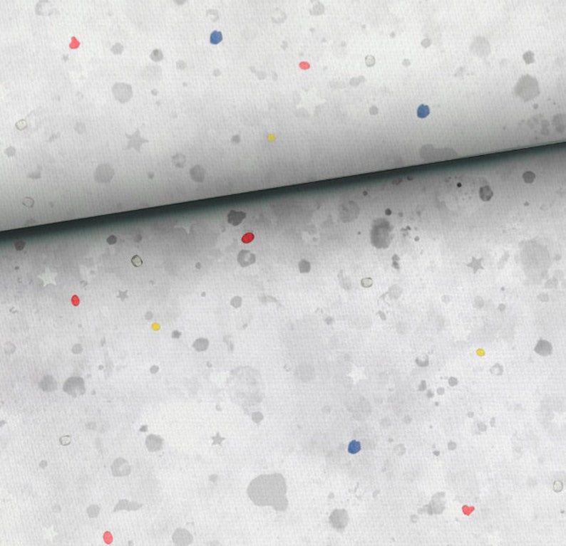 May include: A white fabric with a gray watercolor splatter pattern. The fabric is decorated with small red, blue, and yellow dots and white stars.