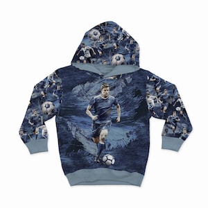 May include: A blue hooded sweatshirt with a repeating pattern of a soccer player dribbling a ball. The pattern is on a blue and white abstract background.