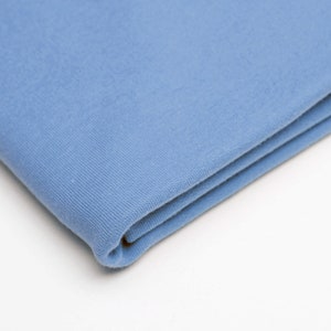 Könnte beinhalten: Ein gefaltetes Stück hellblauen Stoffes. Der Stoff hat eine weiche, strukturierte Oberfläche.