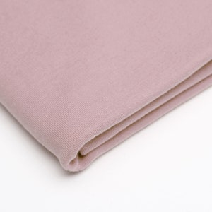 May include: A folded piece of soft, dusty rose colored fabric. The fabric has a slightly textured surface.
