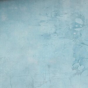 May include: A textured, light blue background with subtle variations in tone and visible brushstrokes. The surface has a distressed appearance, with darker blue patches and fine lines adding depth and visual interest. The overall effect is a soft, muted aesthetic.