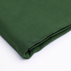 Puede incluir: Un trozo de tela verde oscuro doblado. La tela tiene una superficie suave y texturizada.