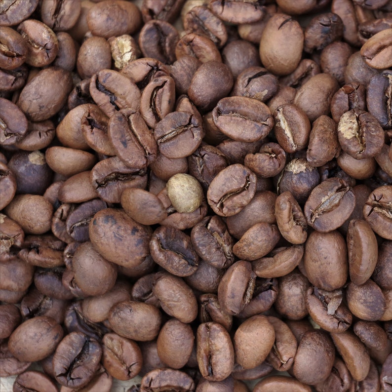May include: A close-up image of a pile of roasted coffee beans. The beans are a rich brown color and have a slightly oily sheen.