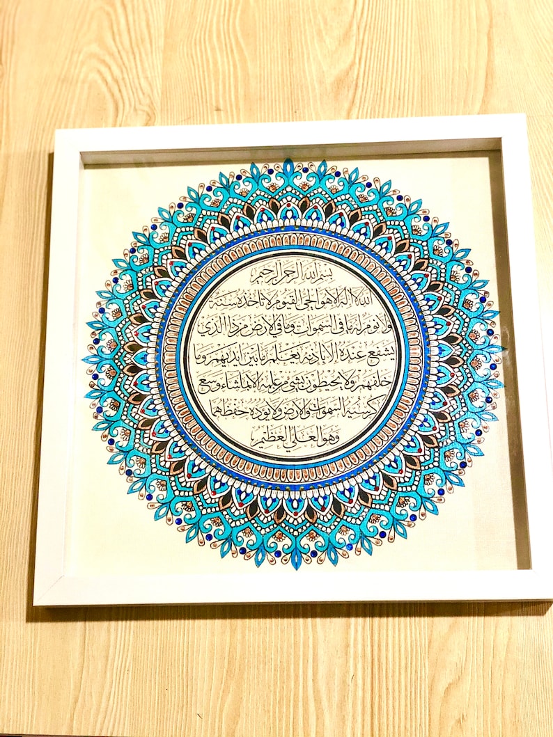 May include: A framed artwork featuring a blue and gold mandala with Arabic calligraphy. The calligraphy reads "Bismillah ir-Rahman ir-Rahim" and continues with a passage from the Quran.