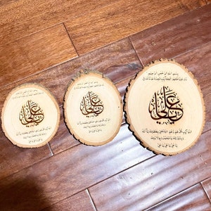 May include: Three wooden round plaques with Arabic calligraphy in gold lettering. The plaques are different sizes and have a natural wood finish.