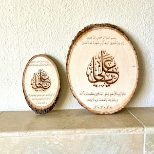 May include: Two wooden round slices with Arabic calligraphy and text in brown ink. The larger slice has the text "Bismillah ir-Rahman ir-Rahim Nad Aliya Mazhar al-Ajaib Tjidhu Awna Laka Fi" and the smaller slice has the text "Bismillah ir-Rahman ir-Rahim 100 D.. Wa Law Aib Kullu Hamm Wa Gham Sayanjalli Bi-Azamatika Ya Allah Wa Binabutika Ya Muhammad Wa Bi-Wilayatika Ya Ali Ya Ali Ya Ali".