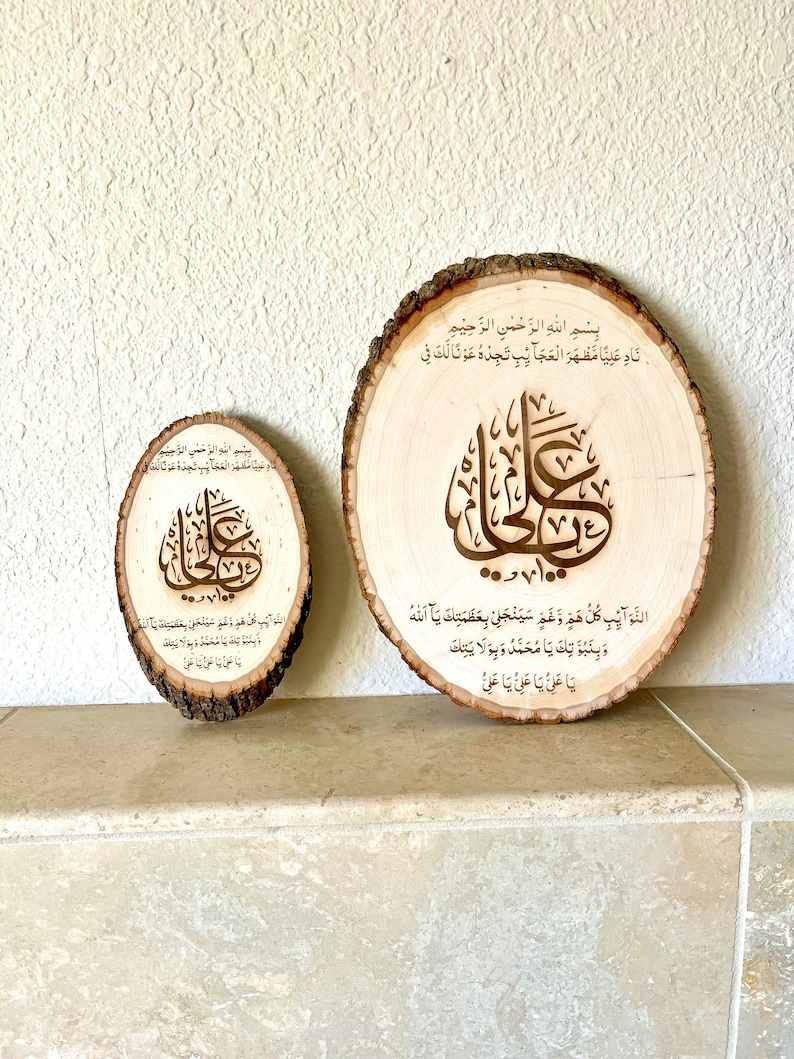 May include: Two wooden round slices with Arabic calligraphy and text in brown ink. The larger slice has the text "Bismillah ir-Rahman ir-Rahim Nad Aliya Mazhar al-Ajaib Tjidhu Awna Laka Fi" and the smaller slice has the text "Bismillah ir-Rahman ir-Rahim 100 D.. Wa Law Aib Kullu Hamm Wa Gham Sayanjalli Bi-Azamatika Ya Allah Wa Binabutika Ya Muhammad Wa Bi-Wilayatika Ya Ali Ya Ali Ya Ali".