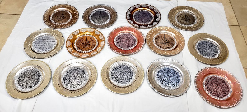 May include: A collection of 15 decorative plates with intricate designs and Arabic calligraphy. The plates are in various colors, including gold, silver, copper, and blue. They are perfect for adding a touch of elegance to any home decor.