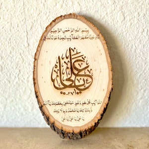 May include: A wooden round plaque with Arabic calligraphy and text in brown. The text reads "Bismillah ir-Rahman ir-Rahim Nad Aliya Mazhar al-Ajaib Tajedeh Awna Laka Fi 100 Da'wa Al-Nawaib Kullu Ham Wa Ghamah Sayanjalli Bi'azamataka Ya Allah Wa Binubuwwatoka Ya Muhammad Wa Biwilayatika Ya Ali Ya Ali Ya Ali."