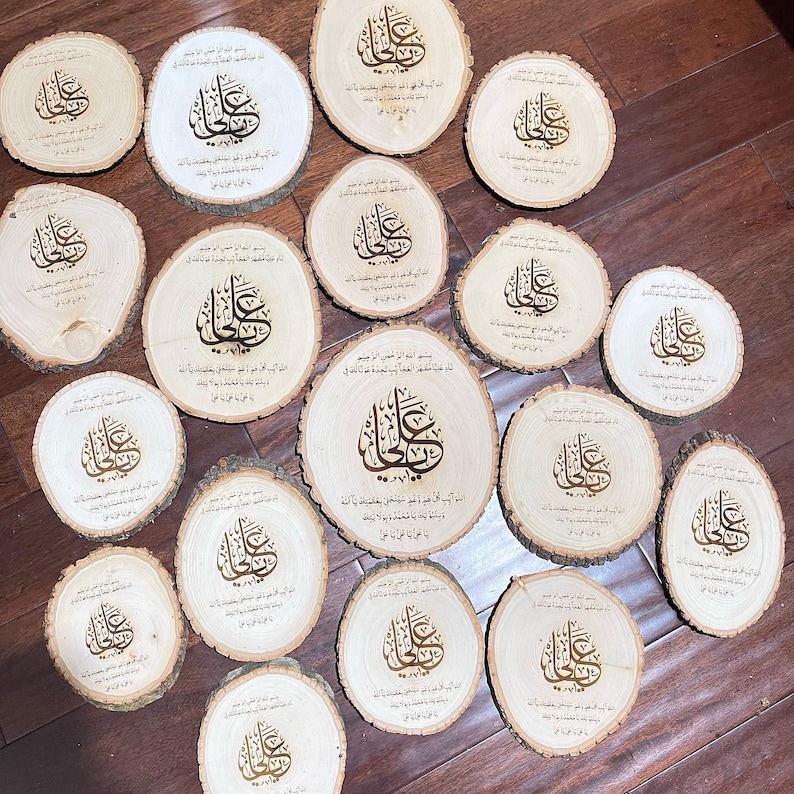 May include: A collection of 15 round wooden plaques with a decorative design and Arabic calligraphy. The plaques are all the same size and shape, and they are arranged in a circle on a wooden surface.