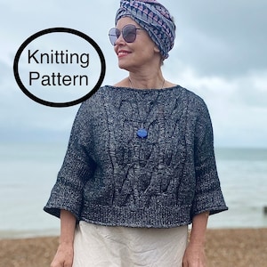 Peut inclure: Une femme portant un pull en tricot noir et blanc avec un motif en câble, un turban blanc avec des motifs géométriques roses et gris, et une longue jupe blanche. Elle se tient sur une plage avec l'océan en arrière-plan. Le texte "Knitting Pattern" est écrit dans un cercle dans le coin supérieur gauche de l'image.