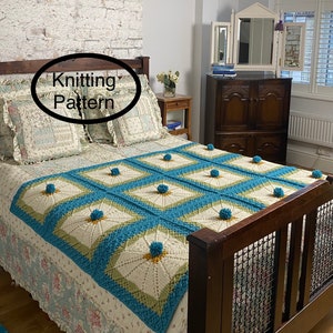 Op de afbeelding: Een wit, blauw en groen gebreid deken met pompoenen op een bed. Het deken heeft een vierkant patroon met een stervormig ontwerp in het midden van elke vierkant. De tekst "Knitting Pattern" is in een cirkel op de afbeelding geschreven.