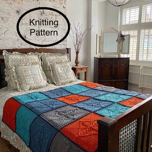 May include: A knitted throw blanket in a patchwork design with squares of orange, blue, and grey. The blanket is on a bed with white ruffled bedding and a wooden headboard.