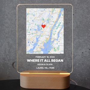 Op de afbeelding: Een gepersonaliseerd LED-nachtlampje met een kaart van New York City, een rode hartmarkering en de tekst "WHERE IT ALL BEGAN". Het licht bevat de datum 18 februari 2023 en de namen Kevin & Olivia.
