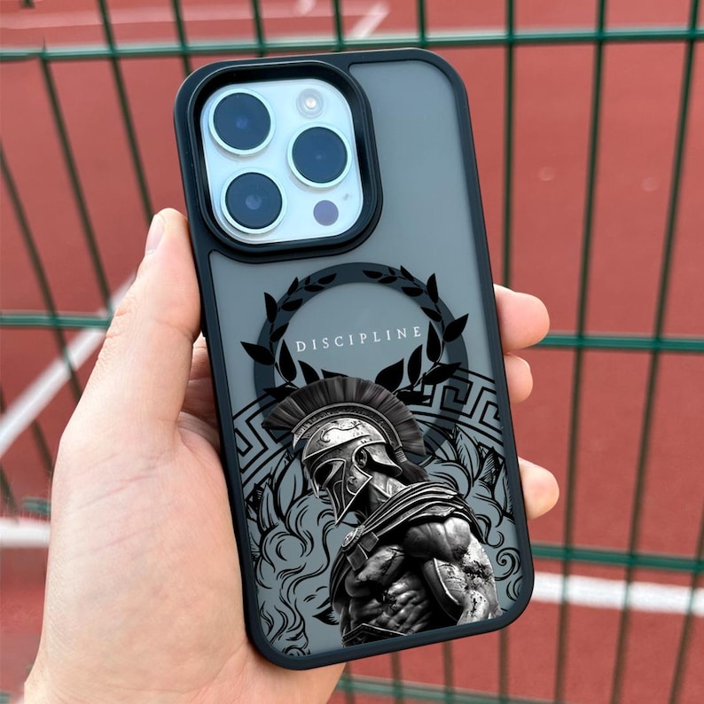 May include: Black phone case with a clear back and a black design of a Spartan warrior with a laurel wreath and the word "DISCIPLINE" on it.